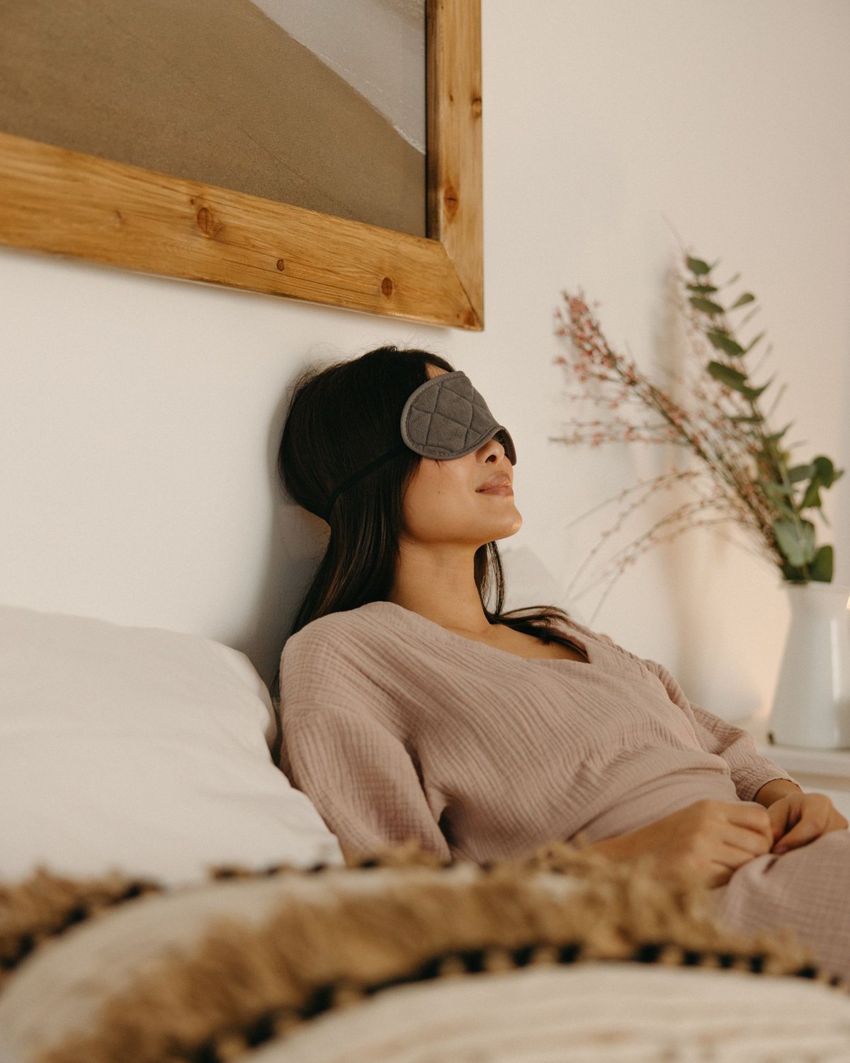 Mujer descansando en la cama con un antifaz para dormir